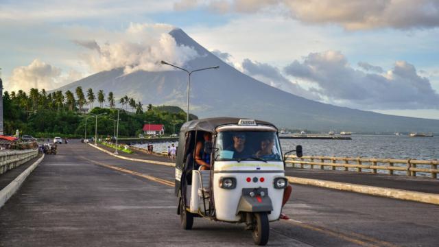 Electric tricycle on a road along Legazpi Bay, Albay, Philippines with Mayon Volcano as background. Photo credit: ADB.