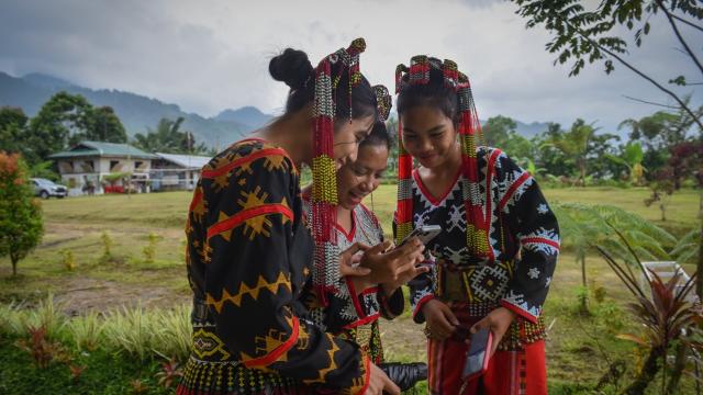 Tboli students in Mindanao looking at a phone. 